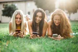 women laying in grass on phones